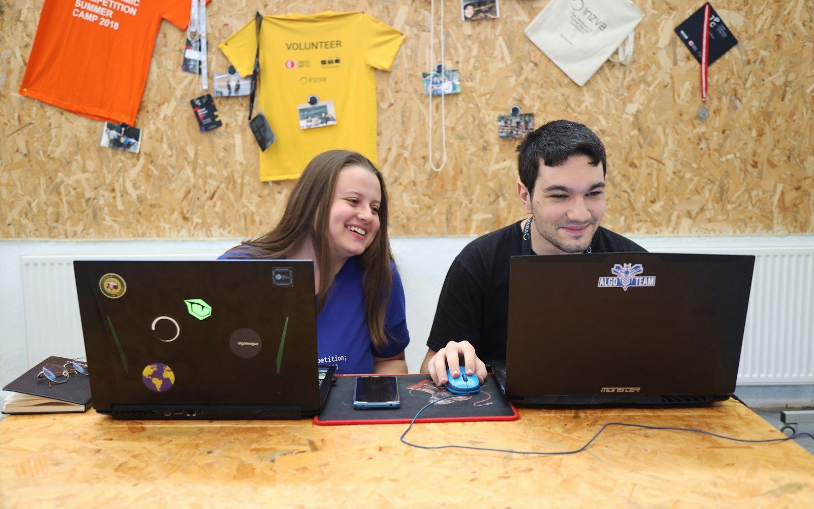 Two young developers smiling at their laptops